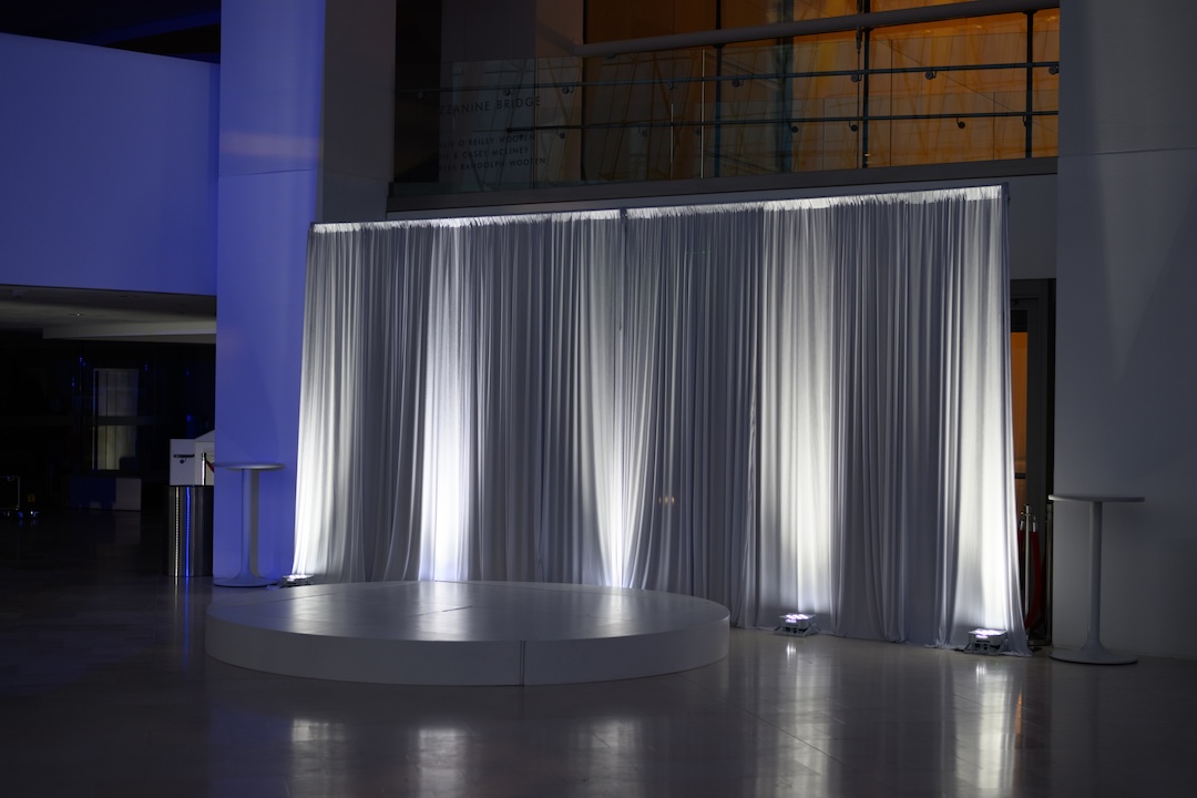 white circle stage and white drape with up lighting